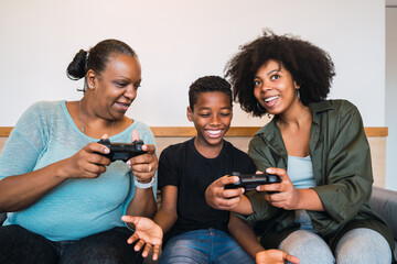 Grandmother, mother and son playing video games at home.