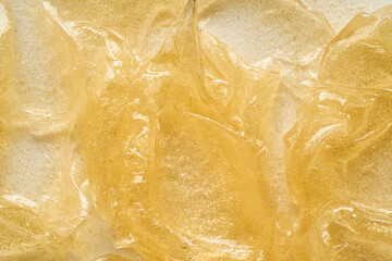 Wall Mural - Transparent smear and texture of golden cosmetic gel on a white background.