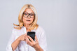© denis_vermenko - Photo portrait of shocked amazed surprised senior mature woman holding mobile phone seeing crazy discounts wearing casual isolated on grey white background.