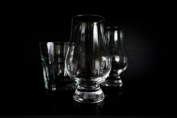 Two empty whisky glasses and a rocks glass on a dark background