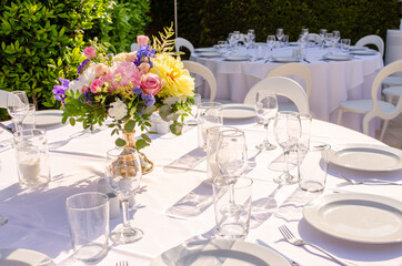 Outdoor dinner table set up with empty dishes and glasson white linen