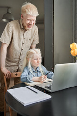 Wall Mural - Man standing behind his blonde daughter while helping to her with homework