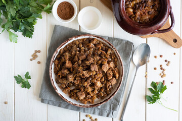 Wall Mural - A hearty meal for the family: lentils with meat and vegetables on a white plate on a white table.