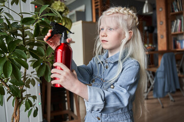 Wall Mural - Girl looking at the house green plants and spraying it with the water