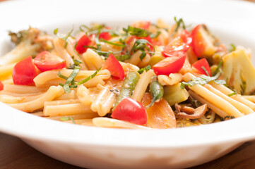 Wall Mural - Closeup shot of vegetable pasta with basil on a white p