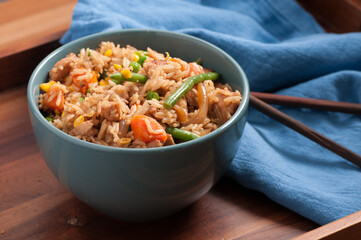 Canvas Print - Closeup shot of homemade fried chicken with rice, vegetables, and chopsticks on a wooden table