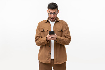 surprised young man in brown shirt looking at his smartphone with amazed facial expression, shocked 