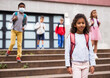 © JackF - Cute curly tween girl with backpack walking with other schoolchildren to school campus after lessons on warm fall day.