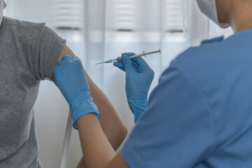 Covid-19,coronavirus hand of young woman nurse,doctor giving syringe vaccine, inject shot to asian arm's patient. Vaccination, immunization or disease prevention against flu or virus pandemic concept.