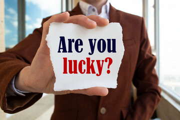 Poster - Closeup on businessman holding a card with ARE YOU LUCKY ? message, business concept image with soft focus background