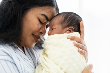 closeup of happy mother carrying and kissing her newborn baby
