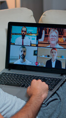 Poster - Over shoulder view of man in pajamas having online conversation with teammates working at online technology project using laptop computer, videoconference web internet communication