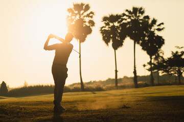 silhouette of a golfer playing swing shot on course in warm sunshine. leisure and sport concept.