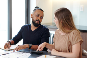 Young couple discussing family budget, checking bills, paychecks and estimating monthly mortgage payment