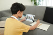 © DragonImages - Teenage boy attending online class, watching lection on tablet computer and writing in textbook