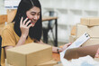 © sarawutnirothon - Woman selling products online talking on the phone and checking stock,Parcel delivery.
