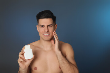 Wall Mural - Handsome man holding post shave lotion on blue background