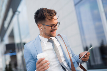 Wall Mural - Smiling businessman holding earphones and cup of coffee