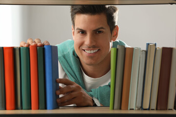 Man searching for book on shelf in library