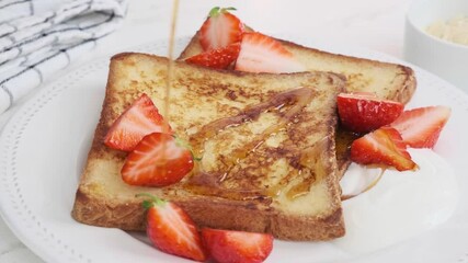 Canvas Print - Pouring maple syrup over French toast with strawberries and cream. Cooking breakfast concept.