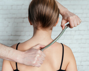 IASTM treatment, girl receiving soft tissue treatment on her neck with stainless steel tool