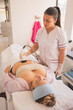 Vertical shot of female physical therapist doing ultrasonic cavitation therapy on a woman in spa