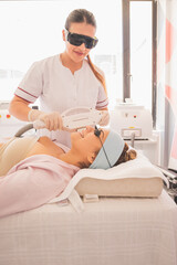 Poster - Vertical shot of female physical therapist doing ultrasonic cavitation therapy on a woman in spa