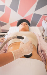 Poster - Vertical shot of female physical therapist doing ultrasonic cavitation therapy on a woman in spa