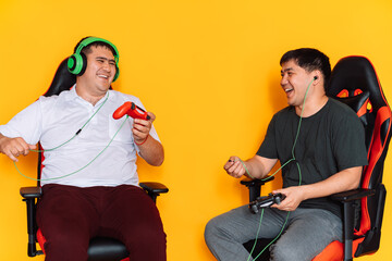 Wall Mural - Two guys laugh and play video games with game controllers