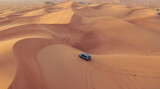 Fototapeta  - AERIAL. Hight flight above car. Desert safari car sand dunning in the Dubai desert during sunset