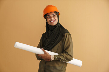 Black muslim woman in helmet smiling while posing with drawing