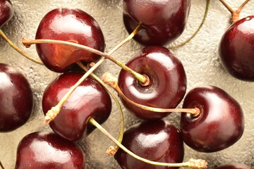 Several ripe organic, dark red cherries on   a metal tray , close-up, top view.