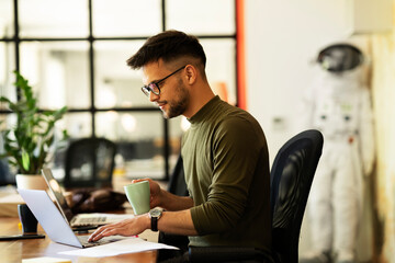 Young businessman using laptop in his office. Handsome man working on laptop