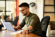 © JustLife - Young businessman using laptop in his office. Handsome man working on laptop