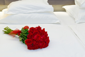 Bouquet of red roses on the bed in a hotel room. Romantic meeting of guests at the hotel honeymoon. romantic getaway for your beloved.