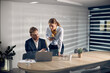 © Drazen - Two business coworkers cooperating while working on laptop in the office.