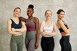 © Drazen - Portrait of happy diverse sportswomen standing against the wall and looking at camera.