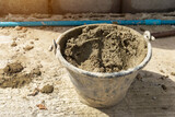 Fototapeta Pomosty - Bucket with construction putty. Cement bucket for construction at a construction site.
