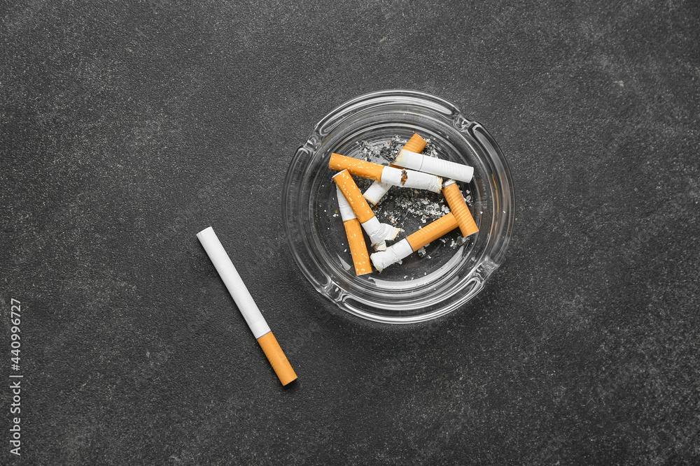 Ash tray with cigarettes on dark background