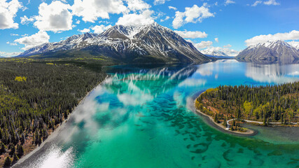 Kathleen Lake, Yukon Territory, Canada. Stunning turquoise green water with reflections of snow capped mountain and clouds. Beautiful boreal forest view of northern Canadian landscape. 