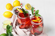 Mason jars of tasty ice tea with fruits on light wooden background
