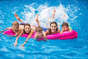 group of children having fun in Pool on the summer time