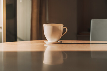 Hot cup of drink on the table in sun light of calm and warm morning.