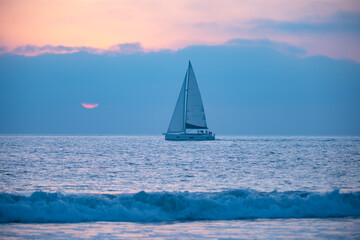  Sailboat on the sea. Sailing boat floating on the blue ocean during sunrise with open main sail.