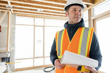Male Homebuilder With Clipboard At Home Construction Site