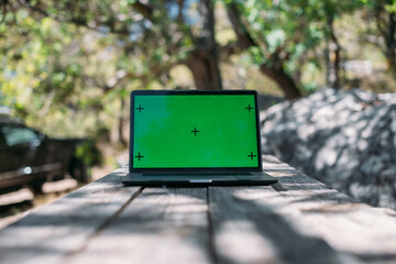 Open laptop on a wooden table in a camping in the mountains