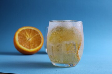 Step-by-step making of lemonade. Step 2. Pour the fruit orange with soda water. A glass of lemonade orange on a blue background with a place for text . close-up