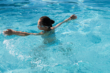 Young girl playing in the swimming pool. Kid outdoor activities. Summer concept. Happy childhood.