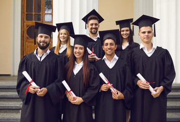 Sticker - Group of happy students in mortarboards and bachelor gowns with diplomas celebrating success on university campus. Education, graduation and people concept.