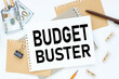 Budget Buster. text on white notepad paper. on a white photo with torn paper